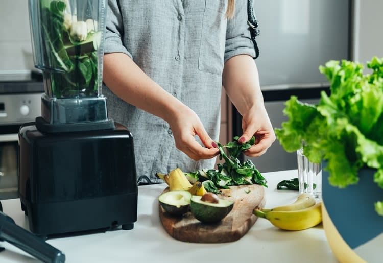 Woman preparing a smoothie on kitchen counter