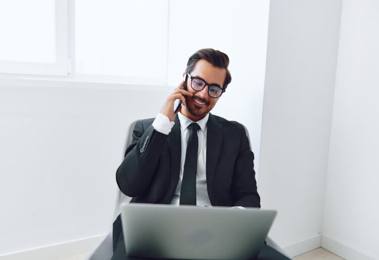 a man in a suit talking on a cell phone while sitting in front of a